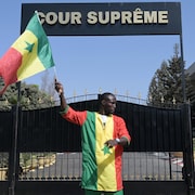 Un militant sénégalais brandit un drapeau national devant la Cour suprême.