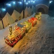 Un train illuminé est immobile sur la neige.