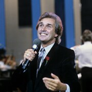 L'homme sourit devant un micro.