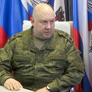 Sergueï Sourovikine en uniforme militaire, assis devant des drapeaux.