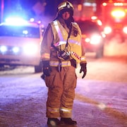 Un pompier du service des incendies à la ville de Québec supervise le déroulement des opérations. Le froid mordant de fin décembre complique la tâche.
Des véhicules d'urgence sont stationnés en arrière-plan, tous gyrophares allumés.