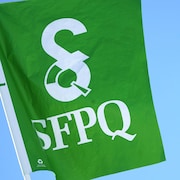 Un drapeau du SFPQ brandi devant l'Assemblée nationale.