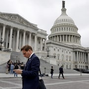 Un homme regarde son téléphone cellulaire devant le Congrès américain.