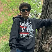 Une personne avec des lunettes soleil posant près d'un arbre