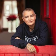 Portrait de la femme appuyée sur le cadre d'une fenêtre rouge. 