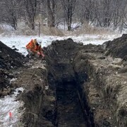 Un trou avec deux archéologues qui effectuent des fouilles.