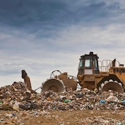 Un bulldozer pousse des déchets dans un site d'enfouissement.
