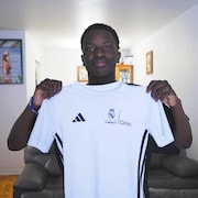 Dans son salon, Bernivens nous montre un maillot blanc sur lequel est inscrit l'embl&egrave;me de la Fondation Real Madrid, avec le mot Clinic &agrave; c&ocirc;t&eacute;. Clinic fait r&eacute;f&eacute;rence au stage.
