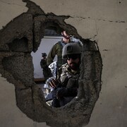 Des soldats derrière un mur de béton.