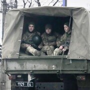 Ils sont assis dans un véhicule militaire.
