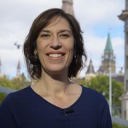 Sophie Chatel pose avec au loin le parlement d'Ottawa.