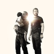 Image promotionnelle du film «Sound of Freedom». Un homme tient ses enfants dans ses bras. Un policier courageux se tient à ses côtés. 
