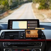 Le tableau de bord d'une voiture avec un gadget de Spotify, devant une route de campagne. 
