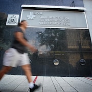 Une personne floue passe devant le quartier général du Service de police de la Ville de Montréal.                                                  