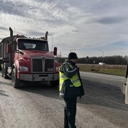 Des agents de la Sûreté du Québec qui circulent entre des camions.
