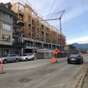 Immeuble en construction avec une grue et des panneaux de restriction de traffic routier dans une rue passante, au centre-ville de Squamish.