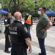 Les agents Michel Yigit et Pasquale Spagnuolo discutent avec les intervenants du square Cabot, dont David Chapman, coordonnateur de Résilience Montréal, un centre dédié au soutien de la population en situation d’itinérance à Montréal.