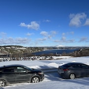 Des voitures sont stationnées devant une rivière l'hiver.