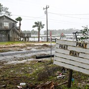 Une marina dévastée où on peut lire « pray, pray, pray » (« prier, prier, prier ») sur un pannonceau.