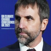 Le ministre est placé devant une affiche de la COP26.