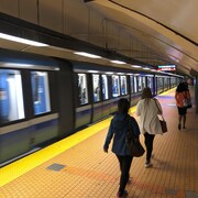 Des gens marchent sur le quai du métro alors qu'un train passe. 