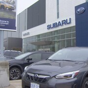 Des voitures de marque Subaru sont stationnées devant le concessionnaire. 