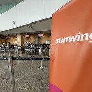 Une bannière Sunwing avec des guichets vides en arrière-plan.