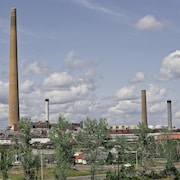 Deux petites cheminées se dressent près de la grande cheminée dans un complexe industriel minier.
