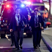 Deux policiers en civil marchent vers la caméra.