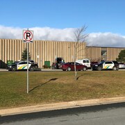 Deux véhicules de la force policière sont garés devant l'école.