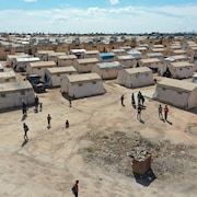 Des personnes marchent dans un camp de déplacés rempli de tentes.