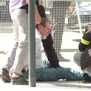Un homme menotté est assis par terre.