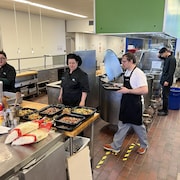 Des étudiants cuisinent dans une cuisine collective.