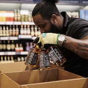 Une personne met des alcools américains dans un carton.