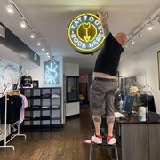 Le directeur d'un salon de tatouage accroche une enseigne dans sa boutique.