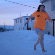 Lucy Tukugarjuk court pieds nus dans la neige.