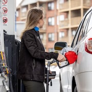 Une femme fait le plein d'essence de son véhicule.