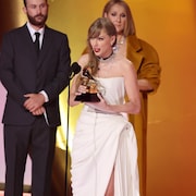 Taylor Swift en robe blanche en train de remercier le public. Céline Dion en arrière-plan.