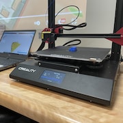 Une imprimante 3D à côté d'un ordinateur portable. 