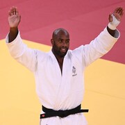 Teddy Riner lèvent les bras dans les airs.
