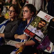 Des personnes regardent des vid&eacute;os hommage en attendant le d&eacute;but de la retransmission en direct de la lib&eacute;ration des otages sur la place des Otages, le 13 octobre 2025 &agrave; Tel-Aviv, en Isra&euml;l.