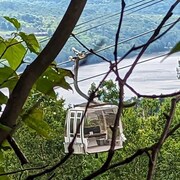 Une télécabine endommagée, et dont un côté est manquant, est suspendue dans la montagne.