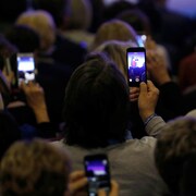 Des participants à un rassemblement du candidat François Fillon en France prennent des images avec leur téléphone.