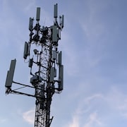 Une antenne de téléphonie mobile avec de multiples récepteurs sous un ciel dégagé.