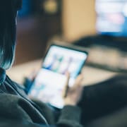 Une jeune femme devant son téléviseur et sa tablette.
