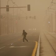 Un piéton traverse la rue pendant une tempête de sable.