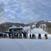 Des skieurs au bas d'une pente de ski font la file pour monter à bord d'un remonte-pente.