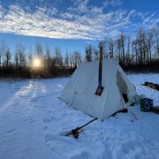 Une tente installée sur de la neige au milieu de la nature. 