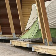 Une tente est installée dans l'une des structures en bois du marché public, au Parc de la Gare.