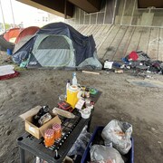 Des tentes et des affaires de sans-abri sous un pont.